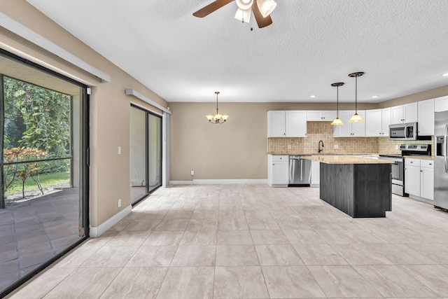 5610 Coach House Cir Unit C, Boca Raton, FL 33486 - kitchen with appliances with stainless steel finishes, a chandelier, white cabinetry, tasteful backsplash, and a textured ceiling