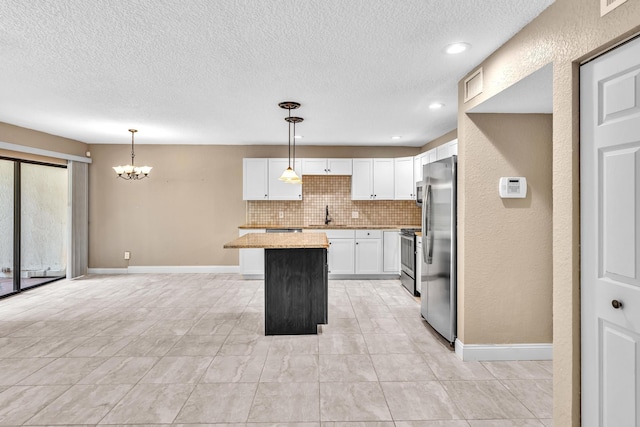 5610 Coach House Cir Unit C, Boca Raton, FL 33486 - kitchen with a chandelier, a kitchen island, a textured ceiling, white cabinets, and tasteful backsplash