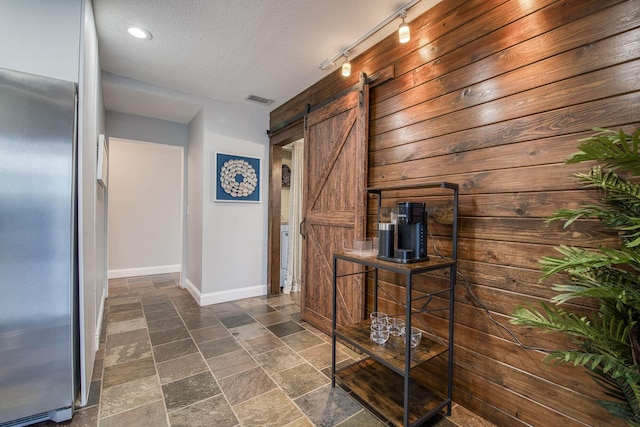 130 S Ocean Breeze, Lake Worth Beach, FL 33460 - hall featuring a barn door, stone tile floors, wooden walls, and a textured ceiling