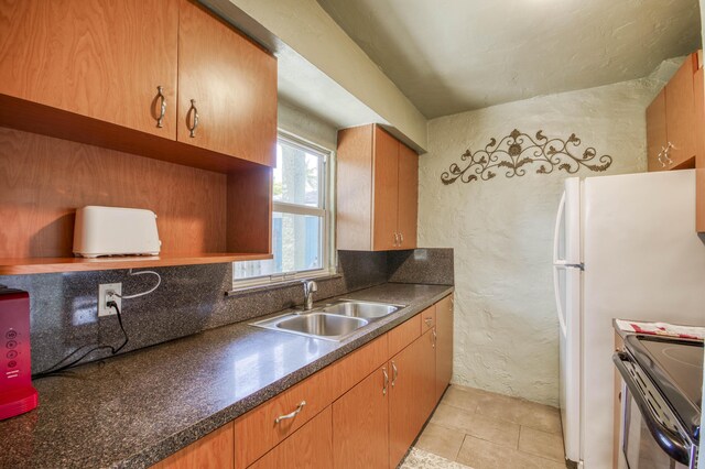 130 S Ocean Breeze, Lake Worth Beach, FL 33460 - kitchen featuring dark countertops, stainless steel range, a textured wall, brown cabinets, and light tile patterned floors