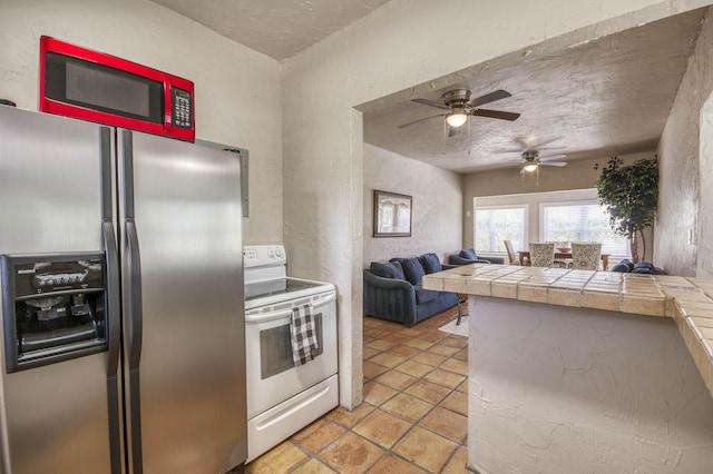 130 S Ocean Breeze, Lake Worth Beach, FL 33460 - kitchen featuring stainless steel fridge, electric stove, ceiling fan, open floor plan, and tile counters