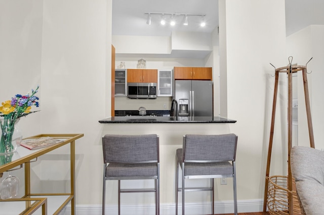 233 S Federal Hwy Unit Uph04, Boca Raton, FL 33432 - kitchen featuring appliances with stainless steel finishes, brown cabinets, a peninsula, a kitchen bar, and glass insert cabinets