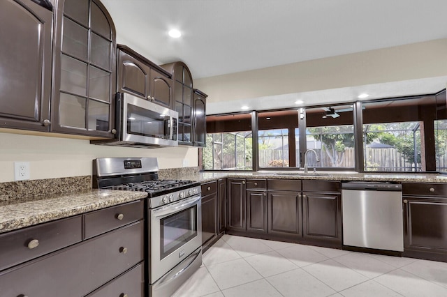 2774 SE Howell Ave, Port Saint Lucie, FL 34952 - kitchen featuring appliances with stainless steel finishes, dark brown cabinetry, glass insert cabinets, light tile patterned floors, and stone countertops