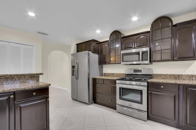 2774 SE Howell Ave, Port Saint Lucie, FL 34952 - kitchen featuring appliances with stainless steel finishes, dark brown cabinetry, light tile patterned flooring, recessed lighting, and glass insert cabinets