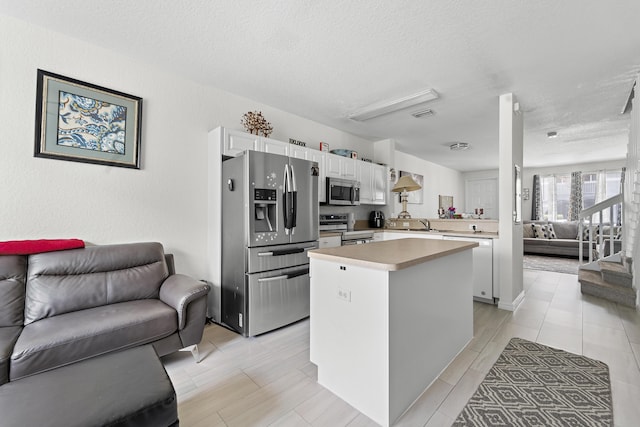 1947 Gardenia Ct, Riviera Beach, FL 33404 - kitchen featuring appliances with stainless steel finishes, open floor plan, light countertops, white cabinets, and a textured ceiling