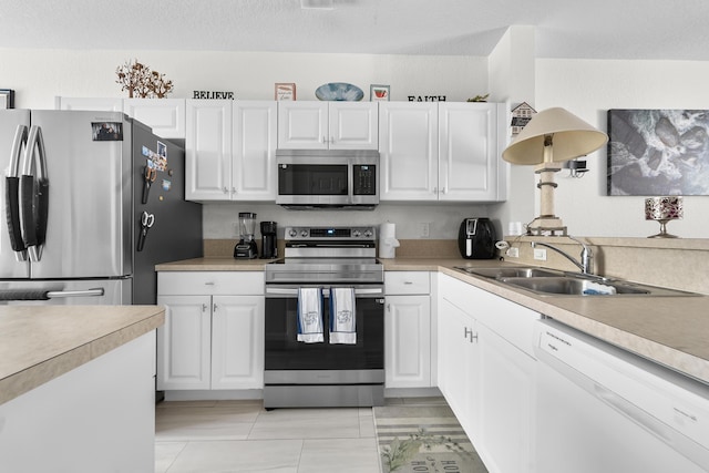 1947 Gardenia Ct, Riviera Beach, FL 33404 - kitchen featuring stainless steel appliances, white cabinetry, light countertops, light tile patterned floors, and a textured ceiling