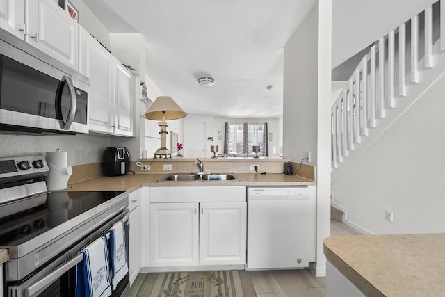 1947 Gardenia Ct, Riviera Beach, FL 33404 - kitchen featuring appliances with stainless steel finishes, white cabinetry, light countertops, and light wood-type flooring