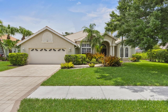 1267 SW Briarwood Dr, Saint Lucie West, FL 34986 - ranch-style house featuring an attached garage, stucco siding, a front yard, and decorative driveway