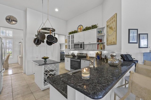 1267 SW Briarwood Dr, Saint Lucie West, FL 34986 - kitchen featuring stainless steel appliances, open shelves, a high ceiling, a kitchen island, and light tile patterned floors