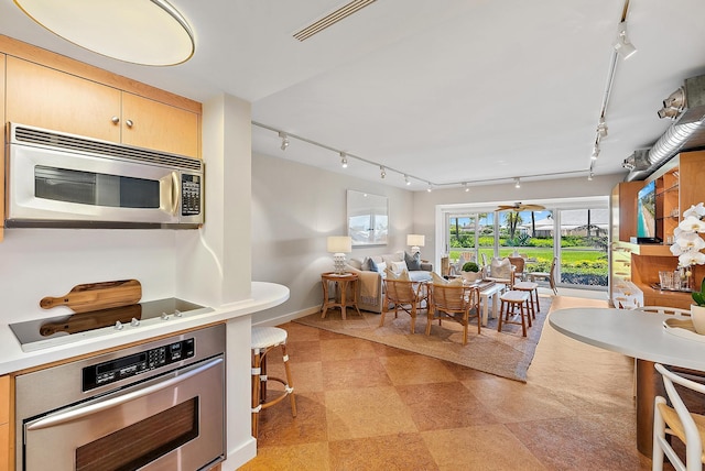 2 Church Ln Unit 115, North Palm Beach, FL 33408 - kitchen with stainless steel appliances, rail lighting, light countertops, and open floor plan