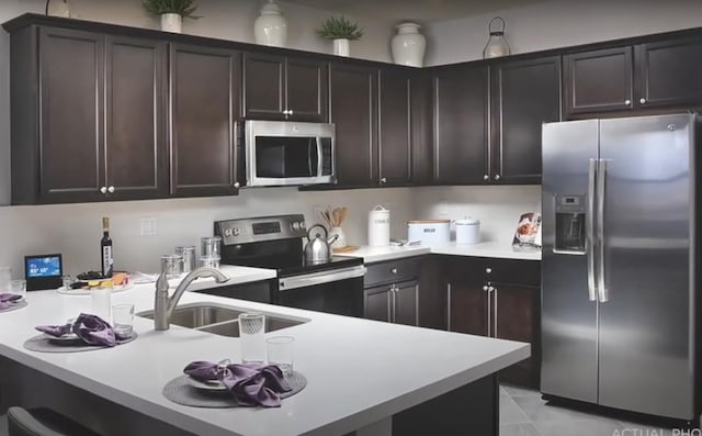 10606 W 33rd Ct, Hialeah, FL 33018 - kitchen featuring appliances with stainless steel finishes, a peninsula, light countertops, and dark brown cabinetry