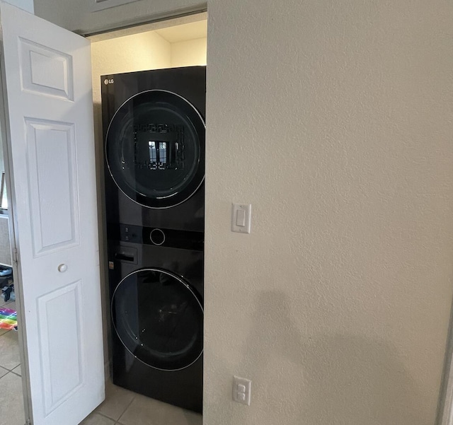 10606 W 33rd Ct, Hialeah, FL 33018 - laundry room featuring stacked washing machine and dryer, light tile patterned floors, and a textured wall