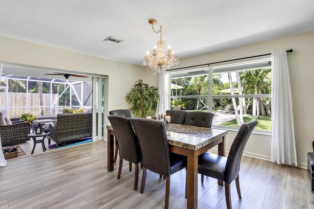 207 Jupiter Woods Dr, Jupiter, FL 33458 - dining area featuring a chandelier, light wood-style floors, a ceiling fan, and a textured ceiling