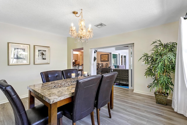 207 Jupiter Woods Dr, Jupiter, FL 33458 - dining area featuring a chandelier, light wood-type flooring, and a textured ceiling