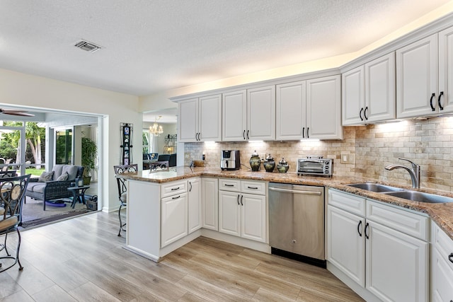 207 Jupiter Woods Dr, Jupiter, FL 33458 - kitchen with dishwasher, backsplash, a textured ceiling, light wood-style flooring, and a peninsula