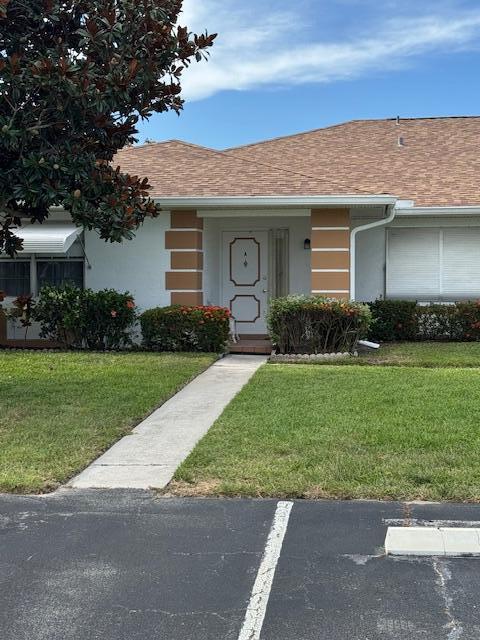 1023 Pheasant Run Dr Unit A, Fort Pierce, FL 34982 - view of front facade featuring a front yard, uncovered parking, and a shingled roof