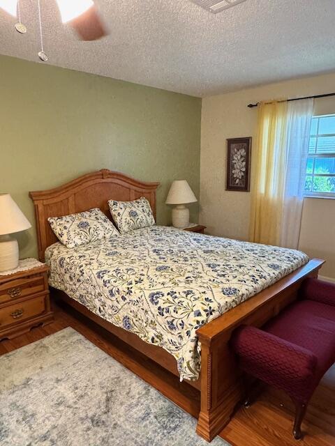 1023 Pheasant Run Dr Unit A, Fort Pierce, FL 34982 - bedroom featuring a textured ceiling, wood finished floors, and a ceiling fan