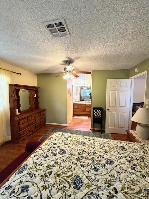 1023 Pheasant Run Dr Unit A, Fort Pierce, FL 34982 - bedroom featuring wood finished floors, a textured ceiling, ensuite bath, and a ceiling fan