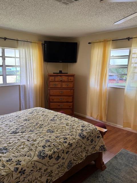 1023 Pheasant Run Dr Unit A, Fort Pierce, FL 34982 - bedroom featuring multiple windows, a textured ceiling, and wood finished floors