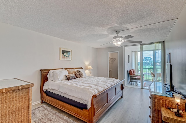 5390 Woodland Lakes Dr Unit 305, Palm Beach Gardens, FL 33418 - bedroom with access to outside, wood finished floors, a textured ceiling, ceiling fan, and a walk in closet