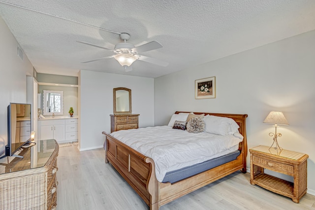 5390 Woodland Lakes Dr Unit 305, Palm Beach Gardens, FL 33418 - bedroom featuring light wood-style flooring, a textured ceiling, ensuite bath, and a ceiling fan