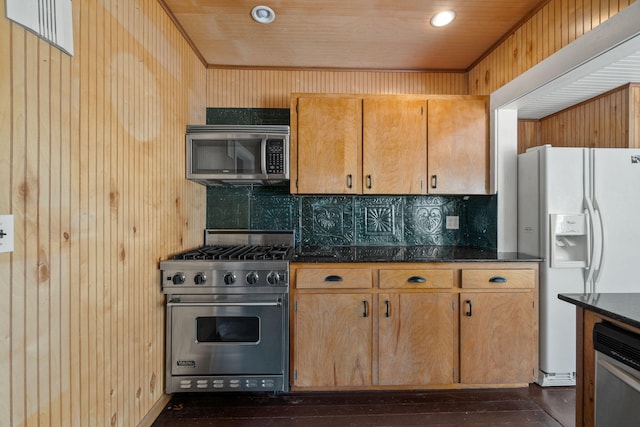 909 N L St, Lake Worth Beach, FL 33460 - kitchen featuring stainless steel appliances, decorative backsplash, wood walls, dark stone countertops, and dark wood-style flooring