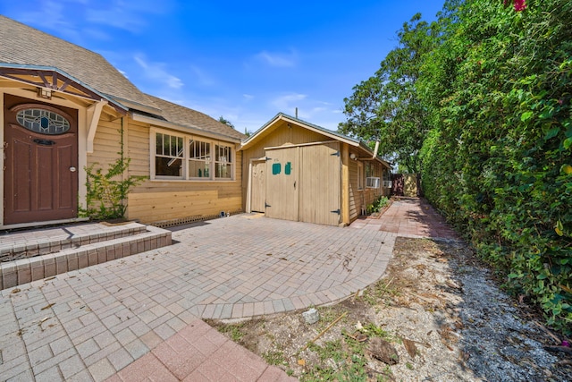 909 N L St, Lake Worth Beach, FL 33460 - view of home's exterior with a patio, an outdoor structure, and roof with shingles