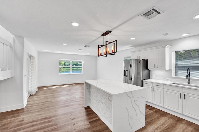 4110 NW 10th St, Delray Beach, FL 33445 - kitchen featuring stainless steel fridge with ice dispenser, a center island, white cabinets, light stone counters, and pendant lighting