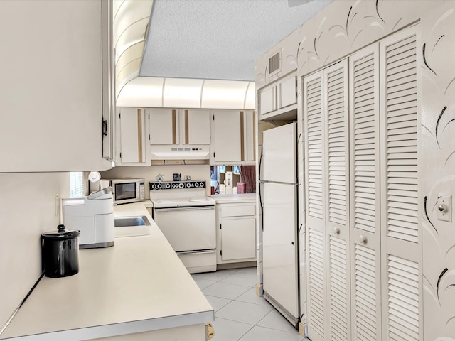 5869 Sugar Palm A Ct Unit A, Delray Beach, FL 33484 - kitchen featuring white appliances, light countertops, under cabinet range hood, light tile patterned floors, and a textured ceiling