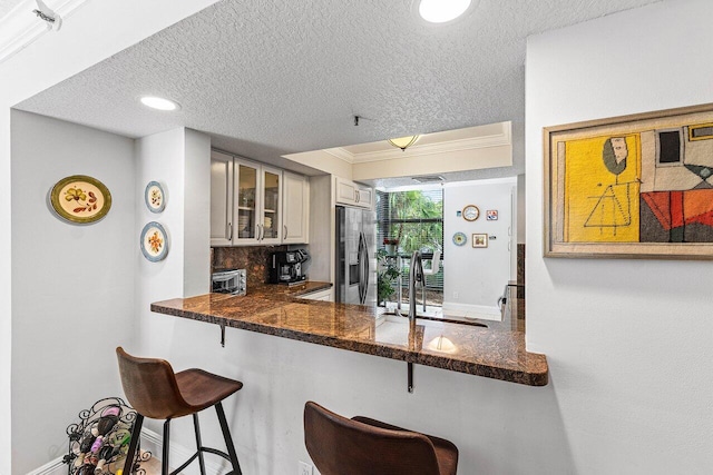 6662 Boca Del Mar Dr Unit 118, Boca Raton, FL 33433 - kitchen with stainless steel fridge with ice dispenser, glass insert cabinets, a textured ceiling, a kitchen breakfast bar, and tasteful backsplash