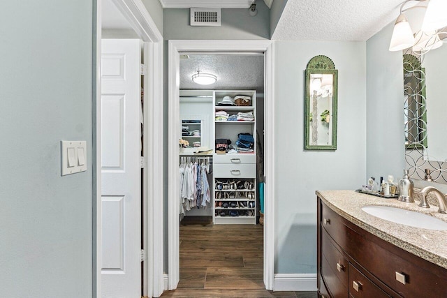 6662 Boca Del Mar Dr Unit 118, Boca Raton, FL 33433 - bathroom with vanity, a textured ceiling, wood finished floors, and a walk in closet
