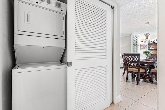 6662 Boca Del Mar Dr Unit 118, Boca Raton, FL 33433 - laundry room featuring stacked washer and clothes dryer, light tile patterned flooring, a chandelier, and a textured ceiling