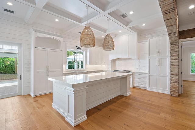 104 Hillcrest Dr, Sewalls Point, FL 34996 - kitchen featuring white cabinets, light countertops, light wood-style floors, a center island, and tasteful backsplash