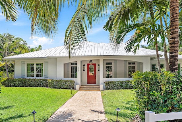 104 Hillcrest Dr, Sewalls Point, FL 34996 - view of front of house featuring stucco siding, a front yard, a metal roof, and a standing seam roof