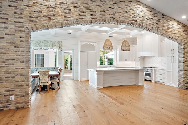 104 Hillcrest Dr, Sewalls Point, FL 34996 - kitchen featuring stainless steel stove, light wood-style flooring, white cabinetry, light countertops, and a center island