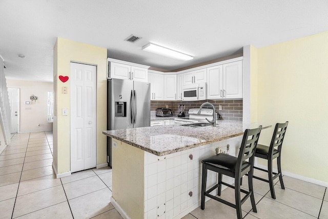 841 Summit Lake Dr, West Palm Beach, FL 33406 - kitchen with white microwave, a peninsula, light stone counters, range, and decorative backsplash