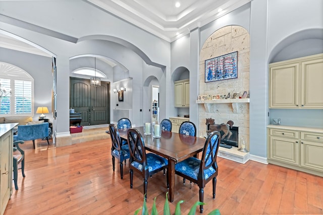 908 SW Squire Johns Ln, Palm City, FL 34990 - dining area featuring light wood-type flooring, a stone fireplace, arched walkways, recessed lighting, and ornamental molding