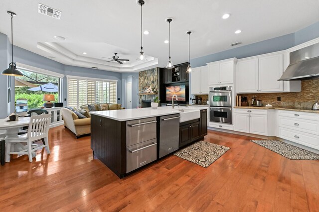 908 SW Squire Johns Ln, Palm City, FL 34990 - kitchen with stainless steel appliances, a tray ceiling, backsplash, ceiling fan, and light countertops
