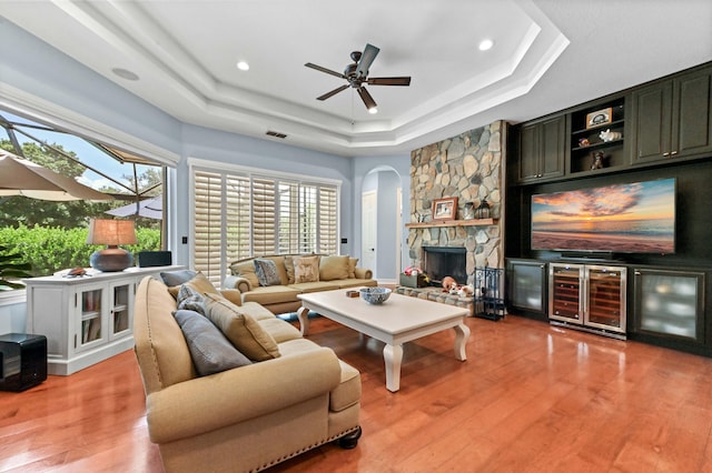 908 SW Squire Johns Ln, Palm City, FL 34990 - living room with beverage cooler, a raised ceiling, arched walkways, a stone fireplace, and a ceiling fan