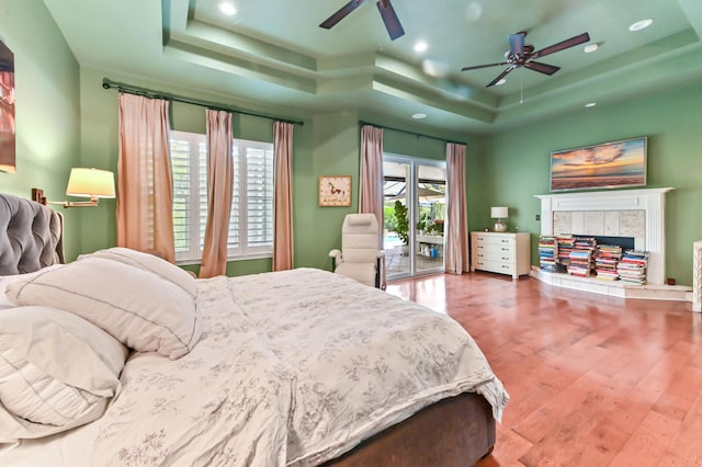 908 SW Squire Johns Ln, Palm City, FL 34990 - bedroom featuring a raised ceiling, access to exterior, wood finished floors, a tile fireplace, and recessed lighting