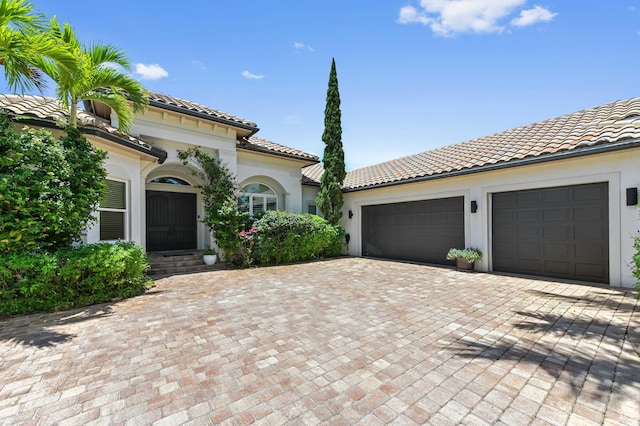 908 SW Squire Johns Ln, Palm City, FL 34990 - mediterranean / spanish-style home with a tiled roof, decorative driveway, a garage, and stucco siding