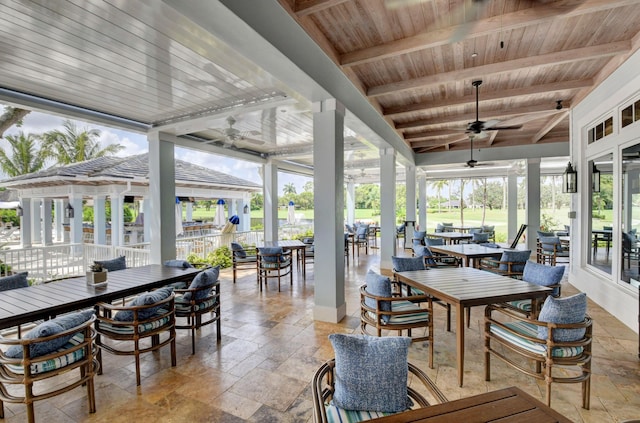 2 Fairway Dr, Boynton Beach, FL 33436 - sunroom / solarium featuring outdoor dining area, ceiling fan, a wood ceiling with exposed beams, and stone tile flooring