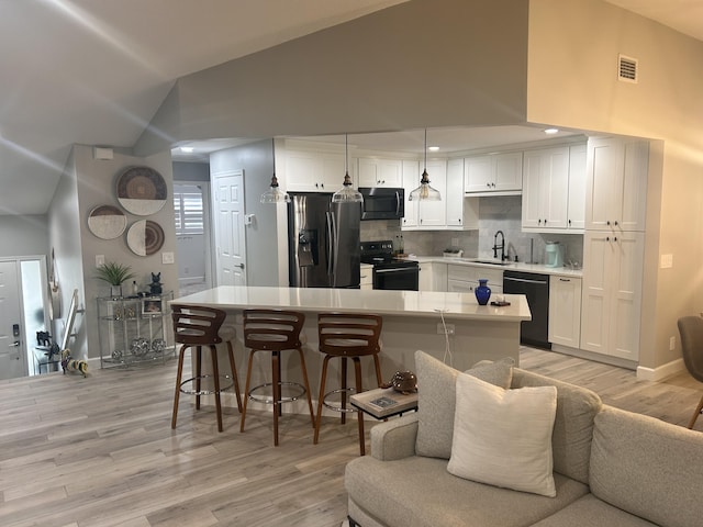 5710 Coach House F Cir Unit F, Boca Raton, FL 33486 - kitchen with black appliances, light wood finished floors, white cabinets, tasteful backsplash, and a kitchen bar