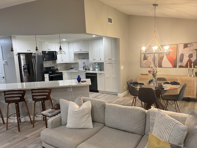 5710 Coach House F Cir Unit F, Boca Raton, FL 33486 - kitchen featuring black appliances, a chandelier, light wood finished floors, light countertops, and white cabinetry