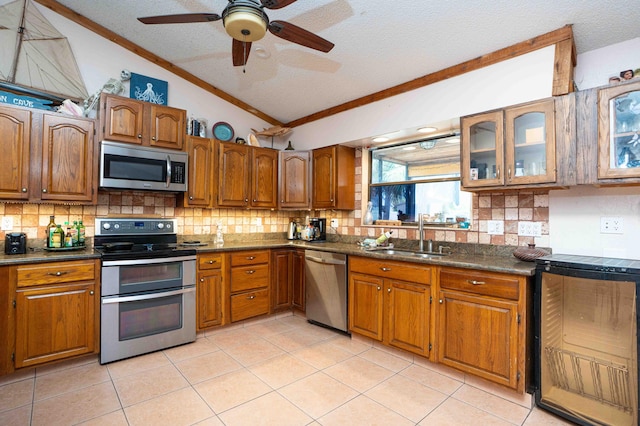 2573 SW Savona Blvd, Port Saint Lucie, FL 34953 - kitchen featuring appliances with stainless steel finishes, vaulted ceiling, crown molding, brown cabinets, and dark countertops