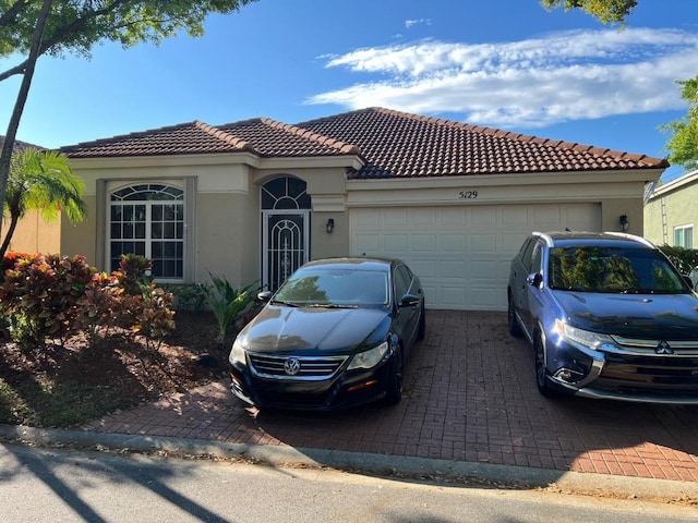 5129 Elpine Way, Riviera Beach, FL 33418 - mediterranean / spanish home with stucco siding, an attached garage, decorative driveway, and a tile roof