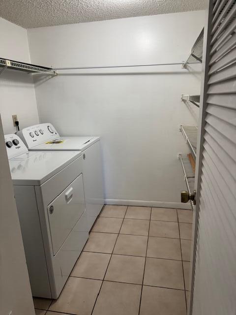 717 Sunny Pine Way Unit A2, Greenacres, FL 33415 - laundry area with washer and clothes dryer, a textured ceiling, and light tile patterned floors