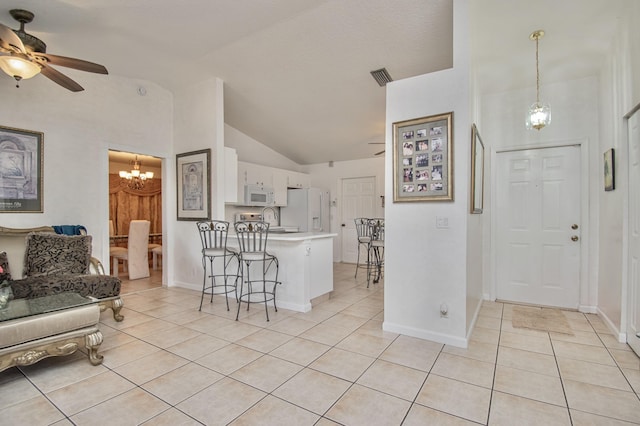 5064 El Claro Cir, West Palm Beach, FL 33415 - kitchen with white appliances, light tile patterned flooring, a peninsula, a chandelier, and high vaulted ceiling