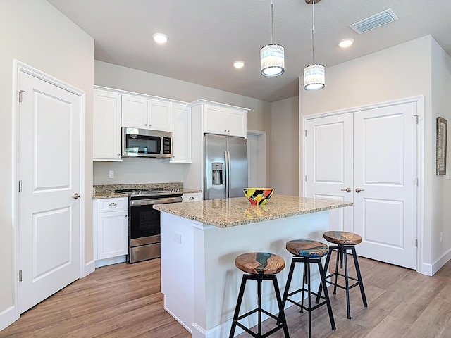 3121 Portofino Blvd, New Smyrna Beach, FL 32168 - kitchen featuring appliances with stainless steel finishes, light wood-style flooring, a kitchen breakfast bar, a center island, and recessed lighting