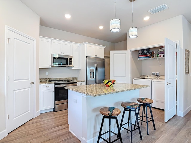 3121 Portofino Blvd, New Smyrna Beach, FL 32168 - kitchen with appliances with stainless steel finishes, washer and dryer, light wood-style floors, a breakfast bar area, and recessed lighting